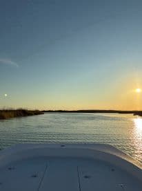 A serene view from the bow of a boat at sunset, showcasing the tranquil waters and surrounding nature — perfect for peaceful evening cruises.