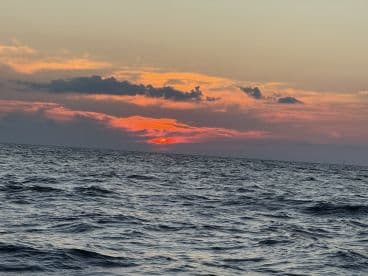 A serene sunset over the ocean, capturing the beauty of nature as the sun dips below the horizon — perfect for tranquil evening boat rides.