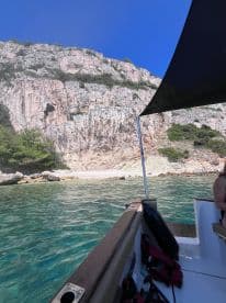 A scenic view from a boat showcasing a stunning rocky coastline and clear waters, perfect for exploring hidden beaches and enjoying a day on the water.