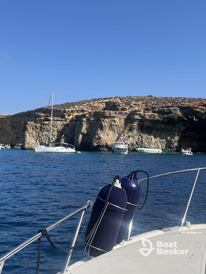 A scenic view of a yacht anchored near stunning cliffs, showcasing the beauty of the coastline and the tranquility of the water.
