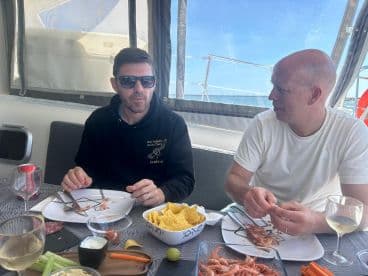 Two guests enjoy a delicious spread of snacks and drinks aboard a boat, perfect for a relaxing day on the water.