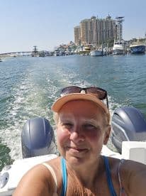 A woman takes a selfie while enjoying a boat ride through a scenic waterway, with a vibrant cityscape in the background — perfect for capturing memorable boating adventures.