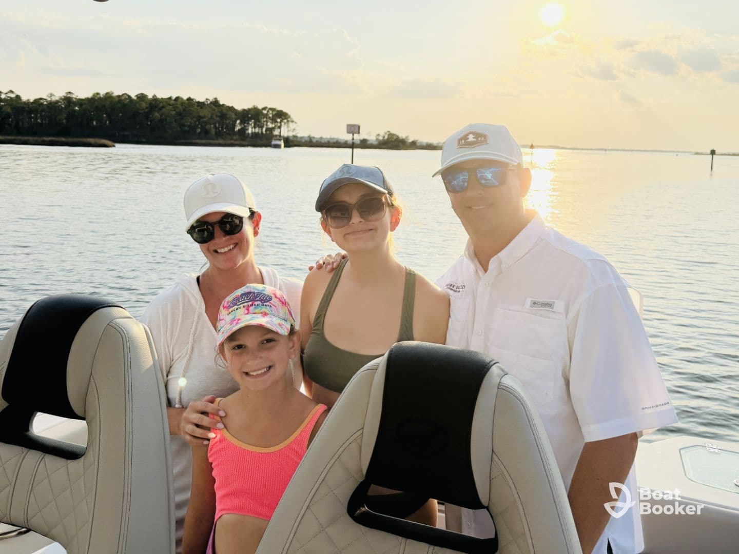 A joyful family poses for a photo on their boat during a beautiful sunset, capturing a memorable moment on the water.