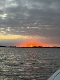 A serene sunset over calm waters, captured from the deck of a boat, creating a picturesque backdrop for evening cruises.