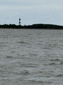 A scenic view of a lighthouse standing tall on an island, surrounded by gentle waves — a perfect backdrop for coastal adventures.