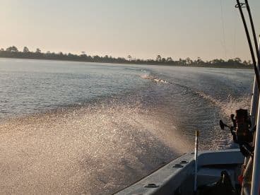 A scenic view of a boat in motion, creating a sparkling wake on calm waters, perfect for showcasing boating adventures.