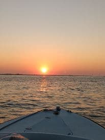 A serene view from the bow of a boat at sunset, showcasing the tranquil waters and vibrant colors of the evening sky — perfect for a peaceful evening cruise.