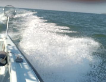 An unclear image of a boat in motion, with water splashes visible but lacking focus and detail.