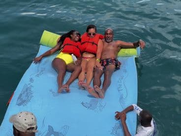 A joyful group enjoys a fun day on a floating mat in the water, showcasing the perfect blend of relaxation and adventure during their aquatic outing.