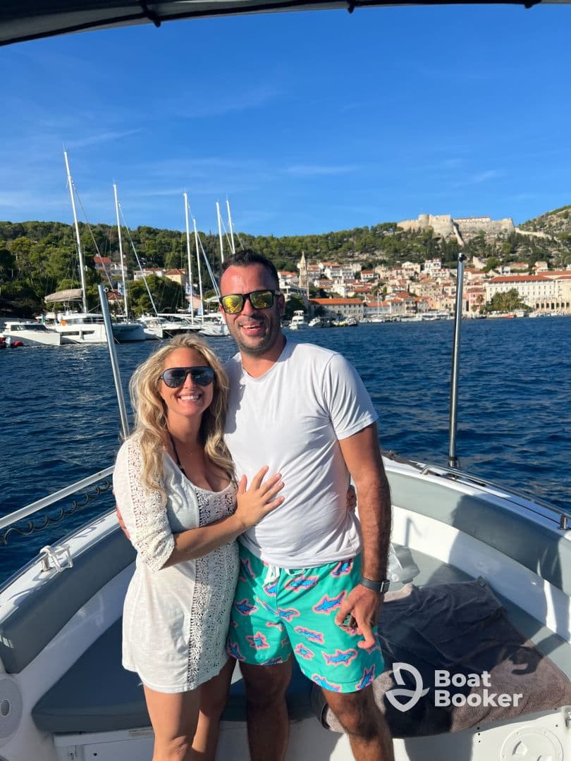 A happy couple poses on the deck of a boat, enjoying a beautiful day on the water with stunning scenery in the background — perfect for romantic getaways or special celebrations.