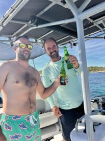 Two friends celebrate with drinks aboard a boat, enjoying a sunny day on the water — perfect for a fun outing or gathering.