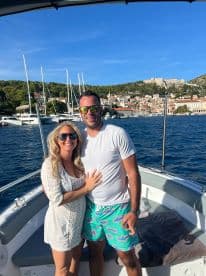 A happy couple poses on the deck of a boat, enjoying a beautiful day on the water with stunning scenery in the background — perfect for romantic getaways or special celebrations.