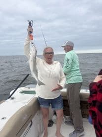 A joyful moment on the water as a woman proudly displays her catch while fishing with friends — a perfect snapshot of fun and excitement during a fishing trip.