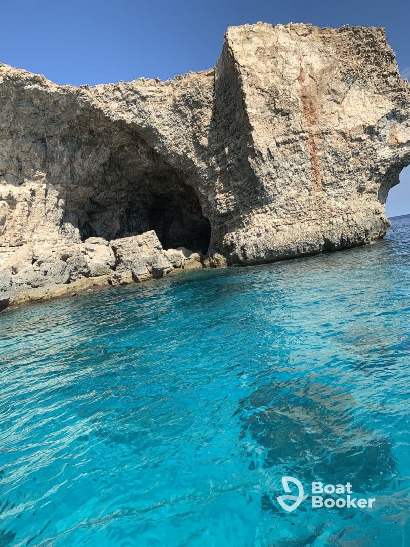 A stunning view of a rocky coastline with crystal-clear turquoise waters, perfect for exploring natural wonders while boating.