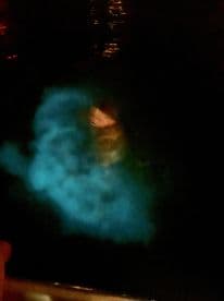 An unclear image showing a person in illuminated water at night, creating a mysterious atmosphere.