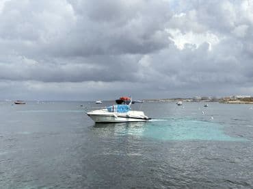 A sleek speedboat navigates through calm waters under a cloudy sky, showcasing the beauty of a day on the sea.