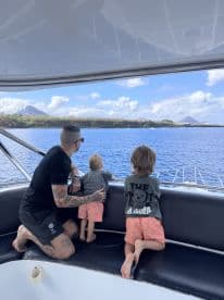 A father and his two children enjoy the scenic ocean view from the comfort of their boat, creating cherished family memories on the water.