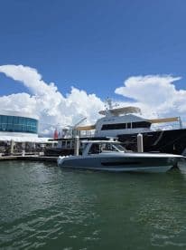 A sleek yacht named 'Spellbound' docked at a marina, showcasing its elegant design against a backdrop of blue skies and fluffy clouds.