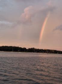 A stunning view of a rainbow arching over tranquil waters at sunset, creating a picturesque scene perfect for nature lovers and photographers.