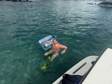 A snorkeler enjoys the clear waters while floating with a pool float, showcasing the fun and excitement of water activities.