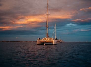 A serene view of a catamaran anchored at dusk, showcasing its elegant lines against a colorful sky — perfect for sunset cruises or tranquil evenings on the water.