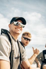 Two friends enjoy a sunny day on the water, showcasing their excitement and camaraderie while wearing life jackets and sunglasses.