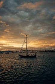 A serene sunset view of a sailboat anchored in calm waters, showcasing the beauty of maritime life against a colorful sky.