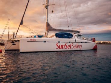 A stunning catamaran named 'SunSet Sailing' docked at sunset, showcasing its sleek design against a colorful sky — perfect for sunset cruises.