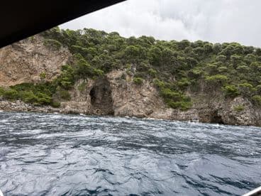 A scenic view of a rocky coastline featuring a cave, with a boat navigating the waters nearby — perfect for exploring natural wonders.