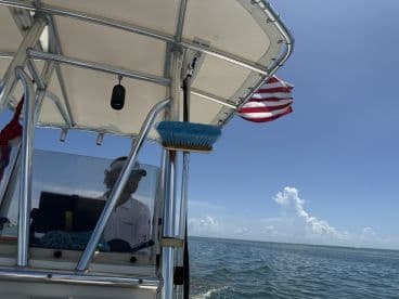 A view of the helm area on a boat, featuring a captain at the controls and a clear blue sky overhead, perfect for a day on the water.