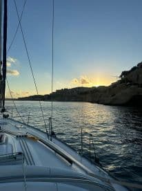 A serene view of a sailboat at sunset, showcasing the tranquil waters and coastal scenery — perfect for peaceful evening cruises.