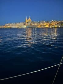 A stunning night view of a city skyline reflecting on the water, showcasing the beauty of the harbor under the evening sky.