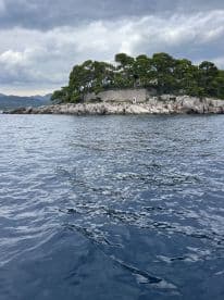 A picturesque view of a rocky island with lush greenery, set against a dramatic sky — a perfect representation of coastal beauty and adventure.