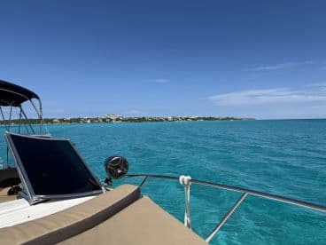 A scenic view of a boat's side as it navigates through crystal-clear turquoise waters, showcasing the vibrant coastline in the background.