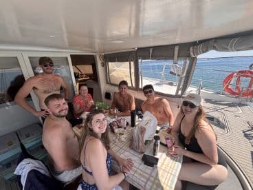 A lively group enjoys a meal together on the deck of a boat, showcasing the perfect atmosphere for socializing and relaxation on the water.