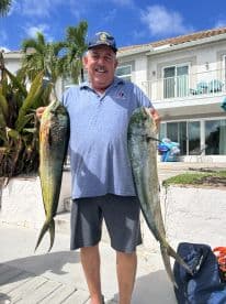 A proud angler displays his impressive catch of two fish, showcasing the excitement of a successful fishing trip.