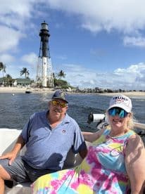 A cheerful couple enjoys a day on the water near a picturesque lighthouse, capturing the essence of a perfect boating adventure.