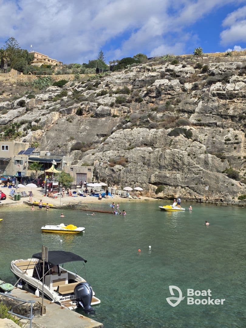 A vibrant scene at a beach with people swimming and enjoying the sun, showcasing the perfect coastal getaway with boats anchored nearby.
