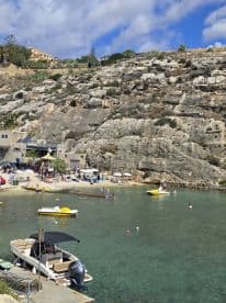 A vibrant scene at a beach with people swimming and enjoying the sun, showcasing the perfect coastal getaway with boats anchored nearby.