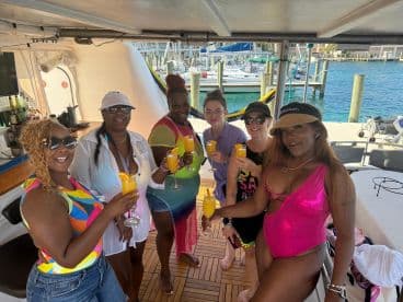 A vibrant group of friends enjoys cocktails aboard a boat, celebrating together in a lively atmosphere — perfect for unforgettable boat parties in the Bahamas.