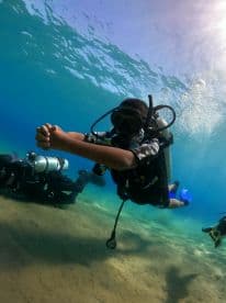 A young diver explores the underwater world alongside fellow scuba divers, showcasing the excitement of underwater adventures and marine exploration.