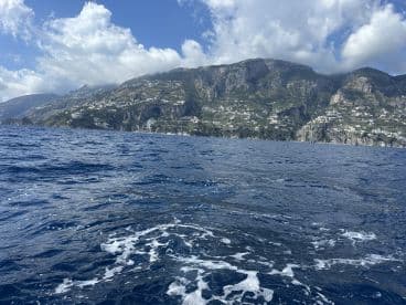 A stunning view of the Amalfi Coast, showcasing dramatic cliffs and picturesque villages along the shoreline — a perfect backdrop for boating adventures.
