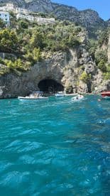 A picturesque view of boats near a stunning coastal cave, surrounded by lush greenery and vibrant turquoise waters — a perfect destination for exploration and adventure.