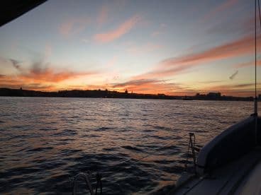 A stunning sunset view from the deck of a boat, showcasing vibrant colors reflecting on the water — perfect for romantic evening cruises.