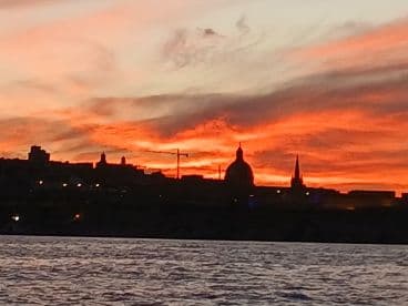 A stunning sunset casts vibrant colors over the skyline, creating a picturesque backdrop for a serene evening on the water.