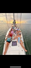 A joyful group of friends enjoys a sunset sailing experience, relaxing on the deck of a yacht while creating unforgettable memories on the water.
