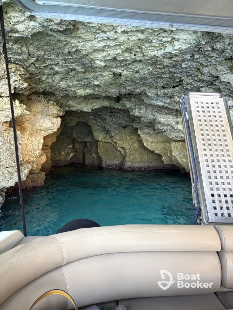 A stunning view of a rocky cave entrance with crystal-clear turquoise water, perfect for exploring hidden gems while boating.