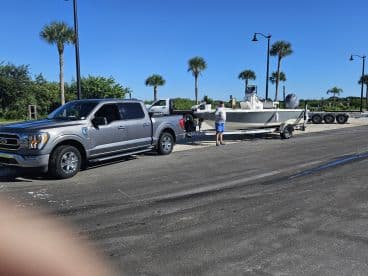 A man prepares a boat for launch at the dock, showcasing the boat and pickup truck in a sunny setting — perfect for a day on the water.