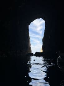 A stunning view from inside a cave, showcasing the serene waters and the sky beyond — perfect for adventure seekers exploring hidden gems.