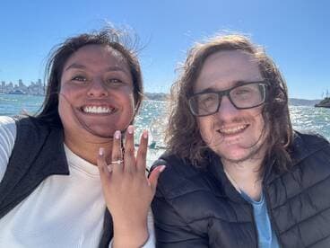 A joyful couple celebrates their engagement on a boat, showcasing the stunning waterfront backdrop — a perfect moment for romantic memories.